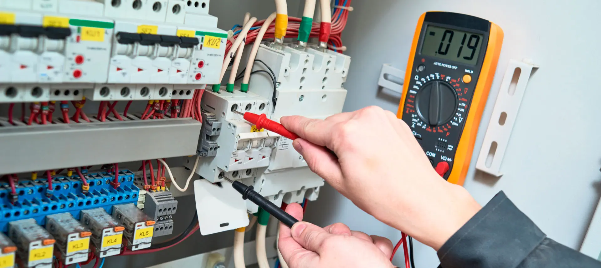 Technician testing an electrical panel with a multimeter