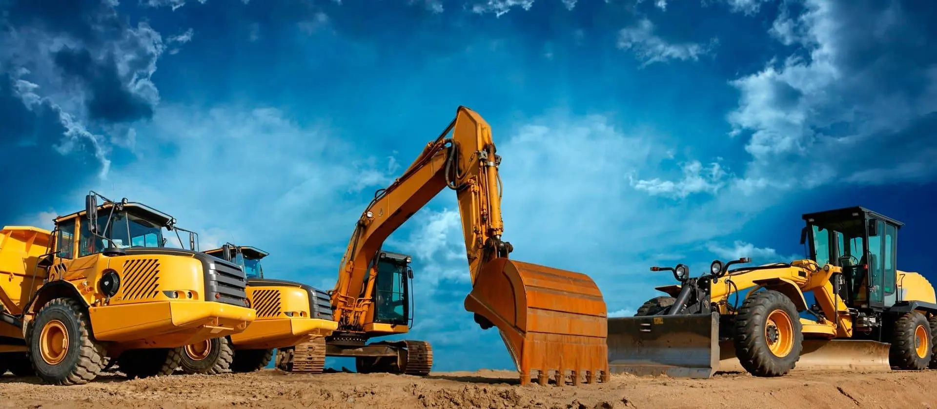 Yellow excavator, dump trucks and grader on an earthworks site